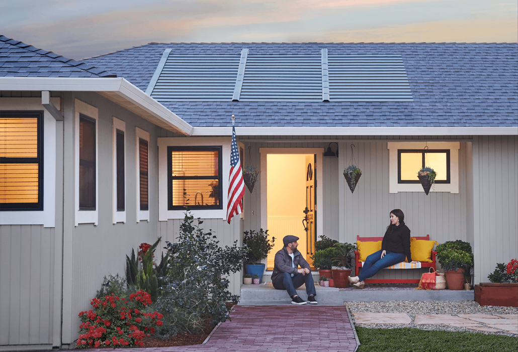 front entrance of home with timberline solar roof installed with homeowners sitting on porch.