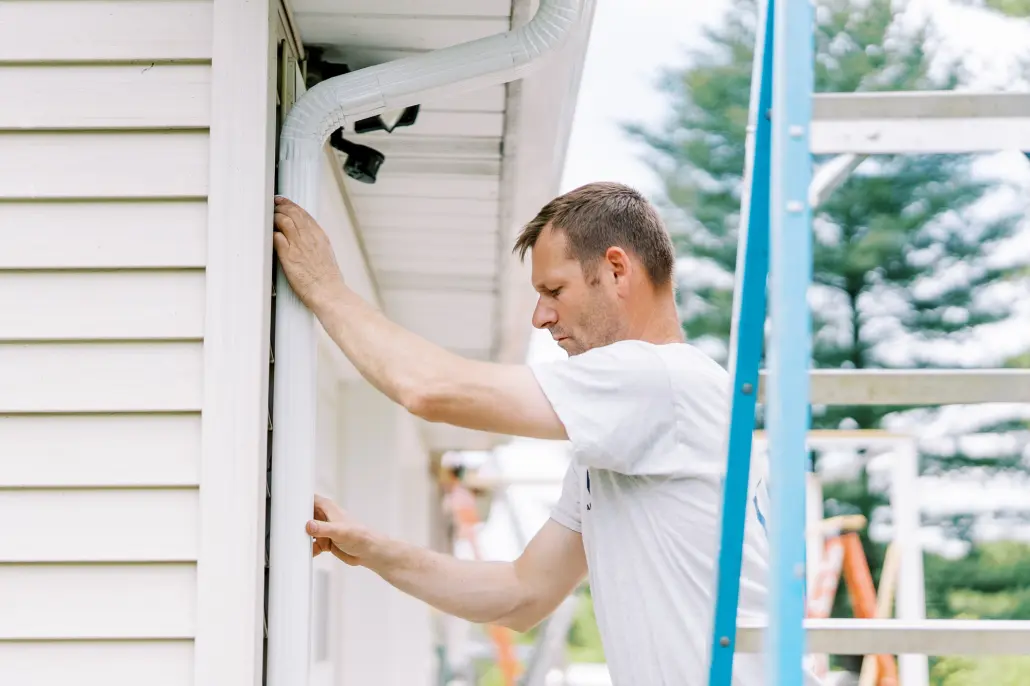 Gutters-1 Valley Roofing team member attaching new gutters to a house.
