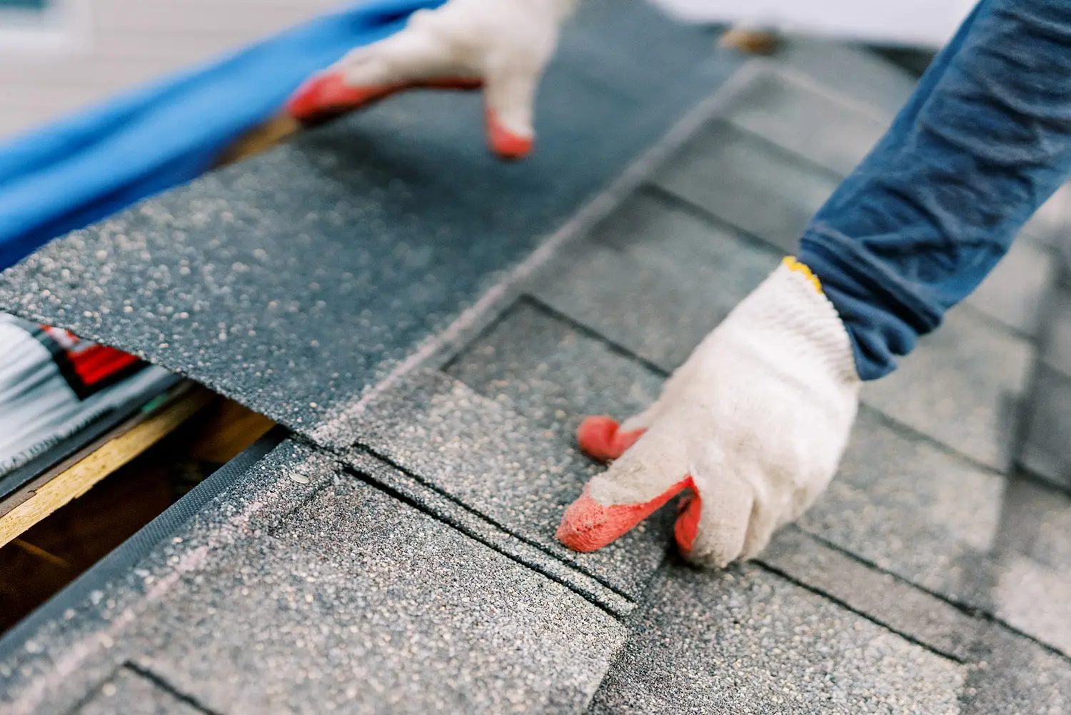 closeup of hands checking shingles during roof inspection