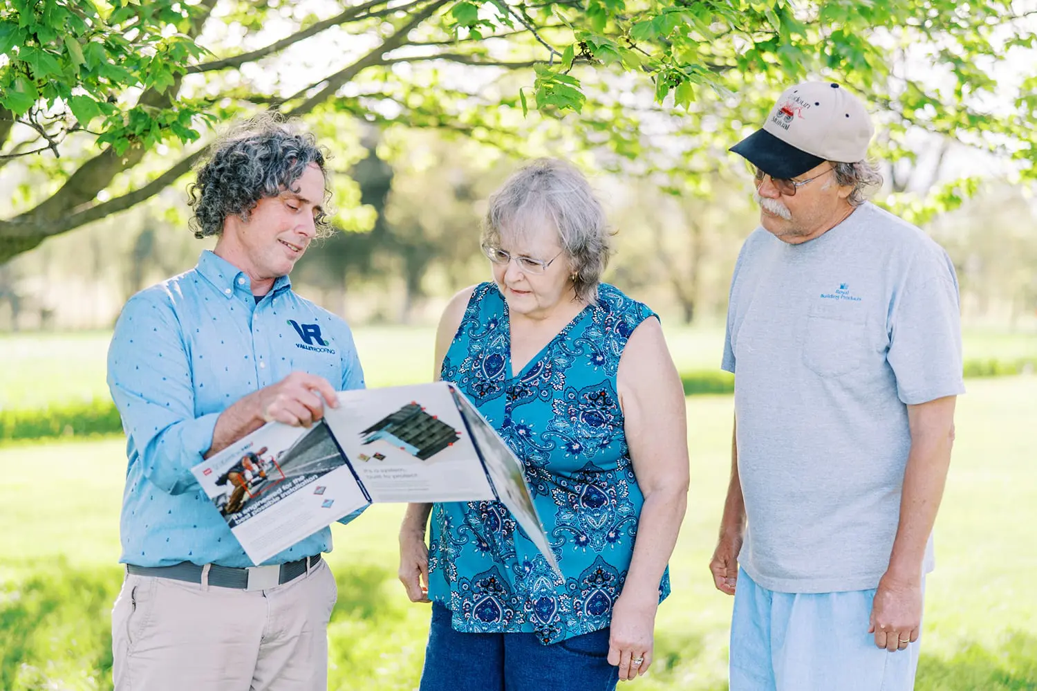 customers with Valley Roofing & Exteriors employee showing them GAF Timberline HDZ® Shingles brochure