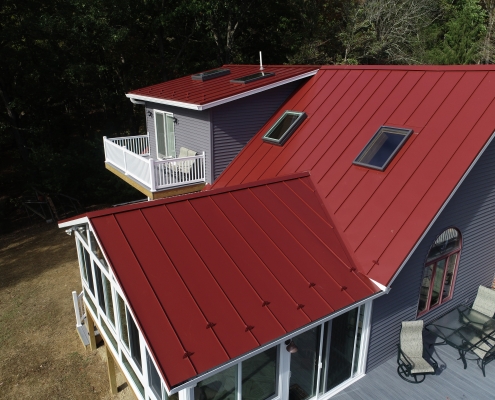 red metal roofing on home with porch and skylights